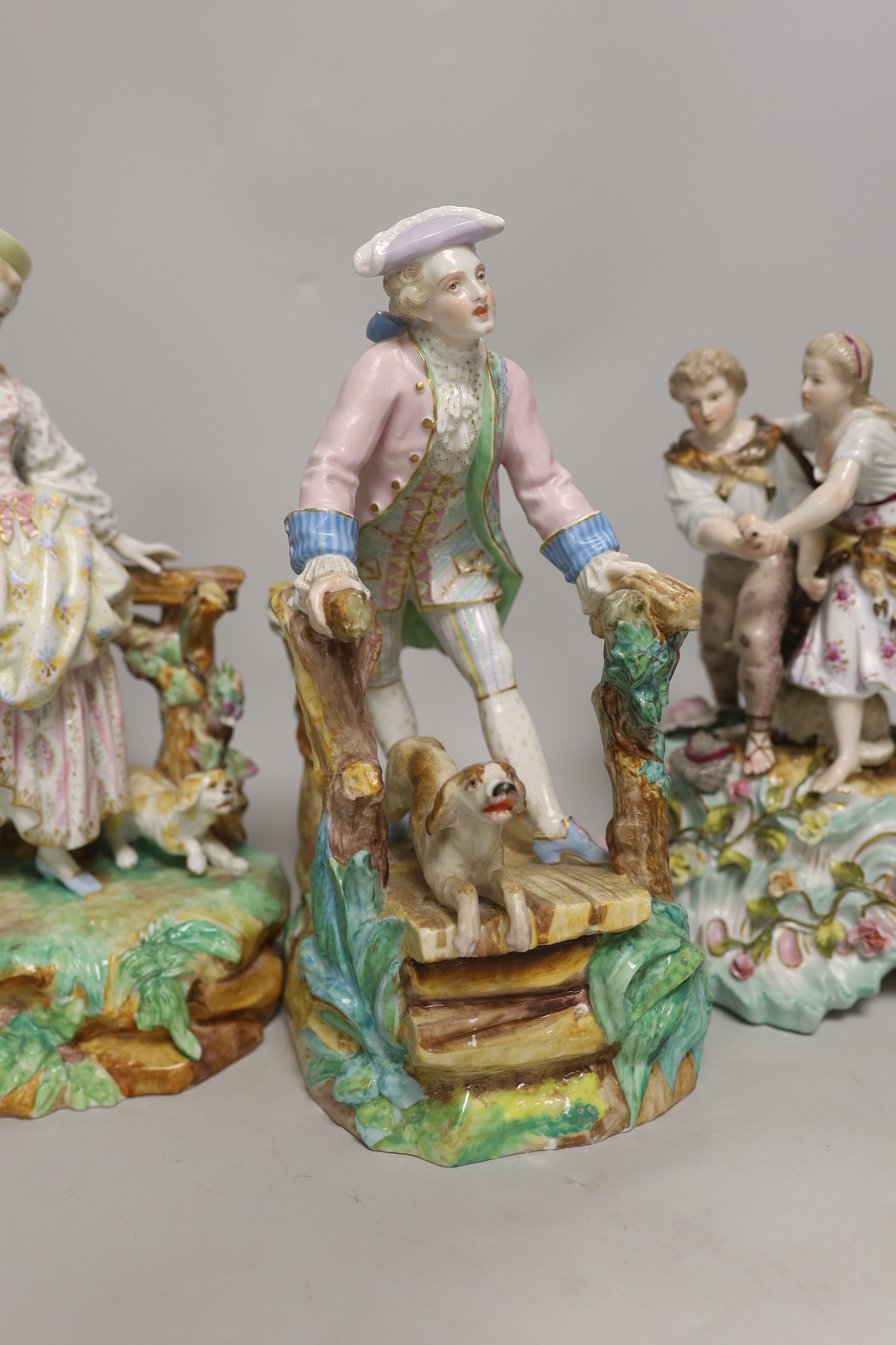 Three German porcelain figures including a Sitzendorf group of a young couple and a sheep, together with a pair of lovers with dogs, highest 28cm